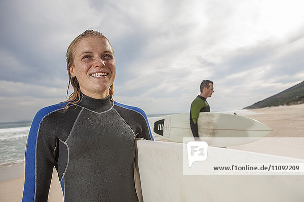 Smiling young woman with surfboard on the beach