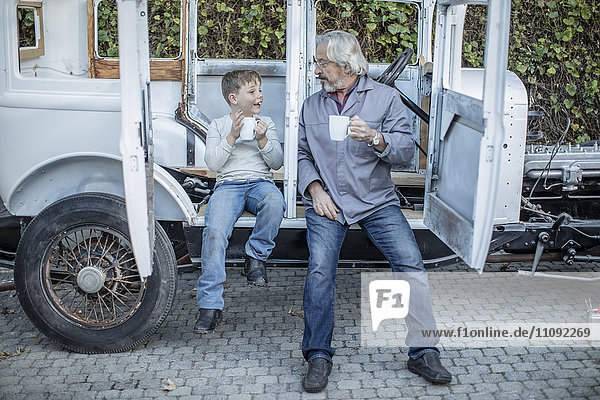 Senior Mann und Junge bei einer Kaffeepause im Oldtimer