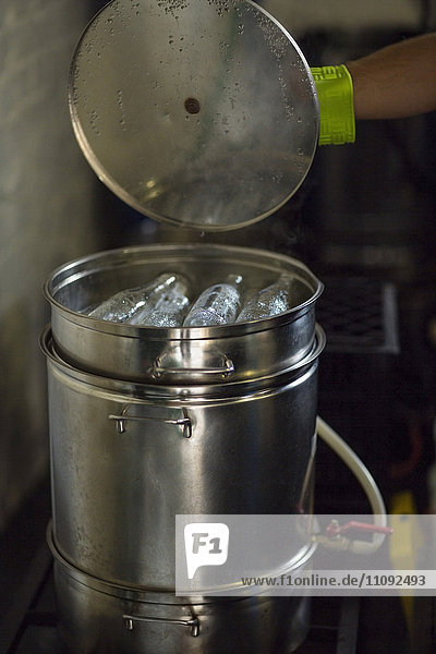 Öffnungsdeckel eines mit gereinigten Flaschen gefüllten Metallbehälters im heißen Behälter