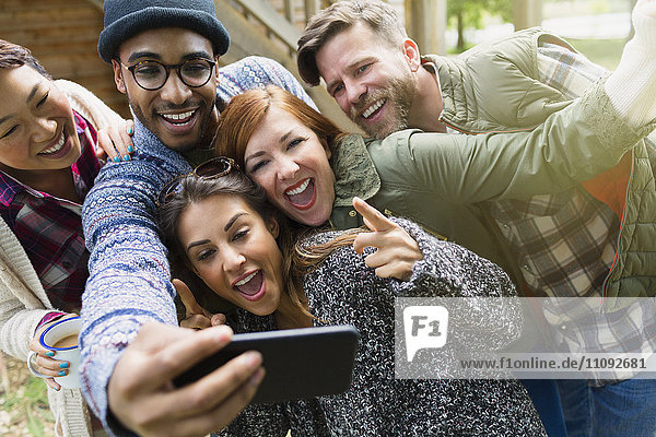 Verspielte Freunde mit Kamerahandygesten  die Selfie nehmen.