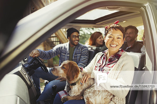 Portrait lächelnde Frau mit Hund auf Schoß im Auto mit Freunden
