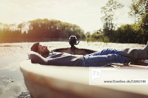 Serene man laying relaxing in canoe on sunny lake