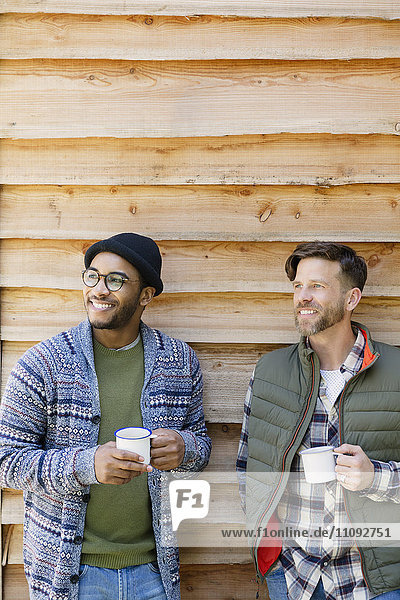 Lächelnde Männer trinken Kaffee außerhalb der Kabine