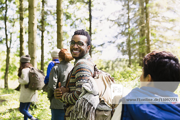 Portrait lächelnder Mann mit Rucksackwanderung in sonnigen Wäldern
