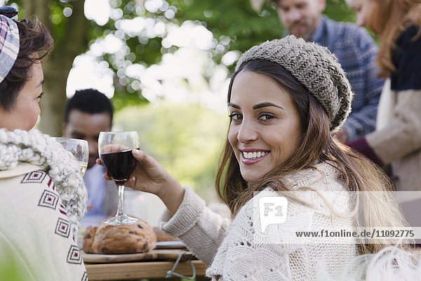 Portrait lächelnde Frau beim Weintrinken auf der Terrasse mit Freunden