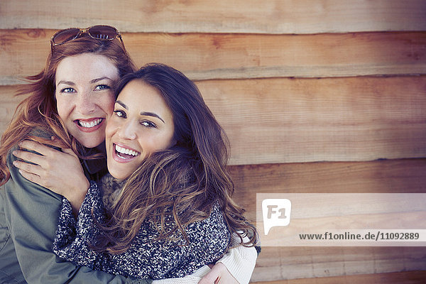 Portrait enthusiastic smiling female friends hugging outside cabin