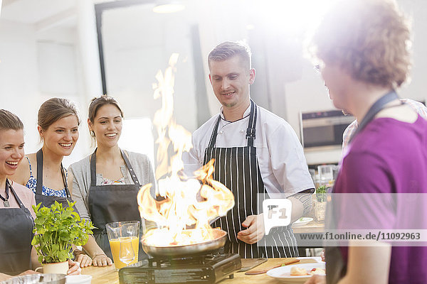 Schüler beobachten Lehrer flambieren in der Küche des Kochkurses