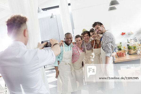 Kochlehrer fotografiert Schüler mit Fotohandy in der Küche des Kochkurses