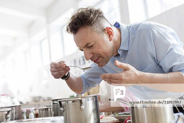 Mann riecht Essen über den Topf gelehnt in der Küche des Kochkurses