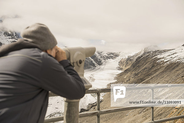 Älterer Mann betrachtet Aussicht mit Fernrohr  Pasterze-Gletscher  Nationalpark Hohe Tauern  Kärnten  Österreich