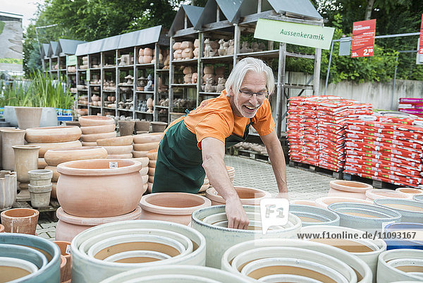 Männlicher Gärtner beim Arrangieren von Keramiktöpfen im Gewächshaus  Augsburg  Bayern  Deutschland