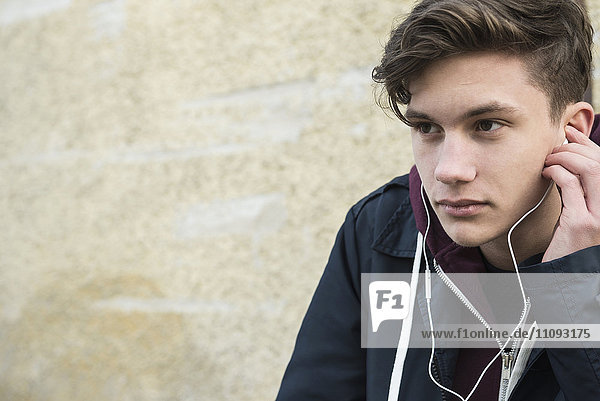 Close-up of young man listening to music with earbud