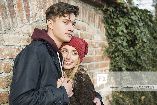 Young couple embracing against brick wall