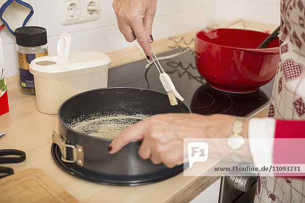 Senior woman preparing food in spring form pan in kitchen