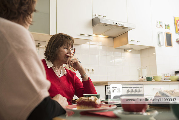 Zwei ältere Frauen führen ein ernstes Gespräch in der Küche