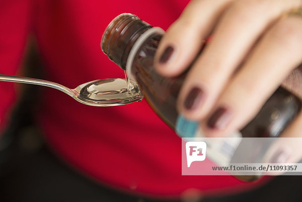 Senior woman pouring liquid medicine in a spoon