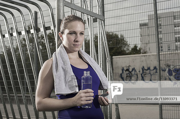 Young woman drinking water on football ground