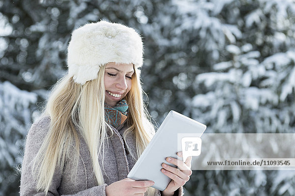 Teenager-Mädchen mit digitalem Tablet und Lächeln im Winter  Bayern  Deutschland