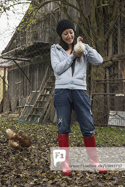 Farmer woman with white chicken bird in farm
