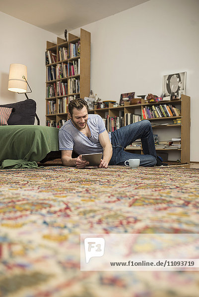 Mid adult man using digital tablet in living room  Munich  Bavaria  Germany