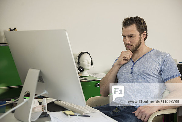 Mid adult man working on computer in living room  Munich  Bavaria  Germany