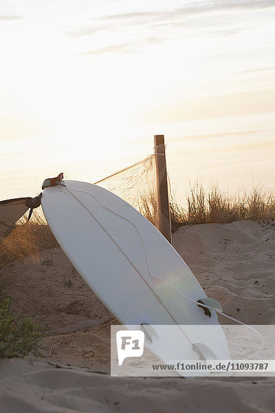 Upside down Surfbrett lehnt gegen Zaun bei Sonnenuntergang