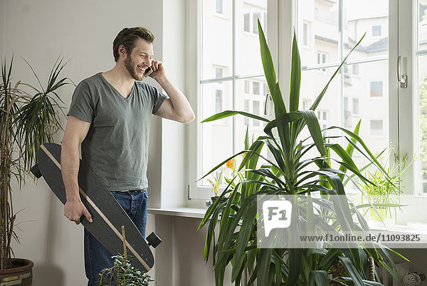 Mid adult man talking on mobile phone in living room Munich Bavaria Germany