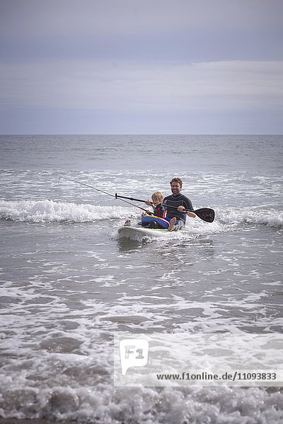 Father with his son paddleboarding and fishing in the sea