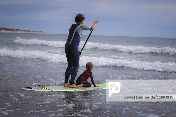 Father with his son paddleboarding in the sea