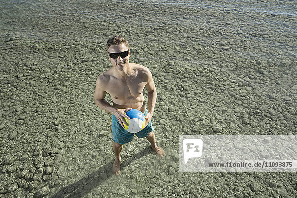 Mature man playing volleyball in lake  Bavaria  Germany