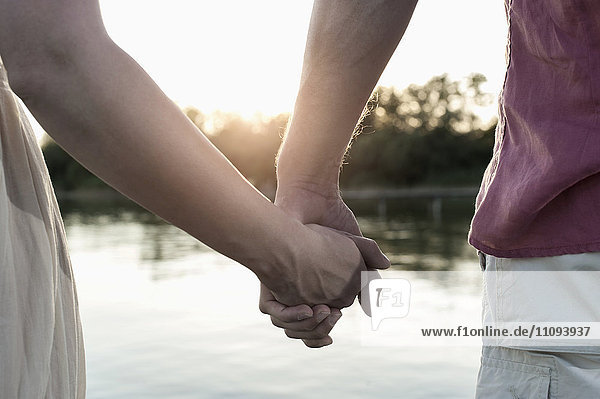 Mittelansicht eines verliebten Paares  das sich bei Sonnenuntergang die Hände hält  Bayern  Deutschland
