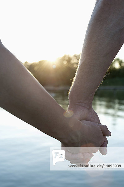 Nahaufnahme eines verliebten Paares  das sich bei Sonnenuntergang die Hände hält  Bayern  Deutschland
