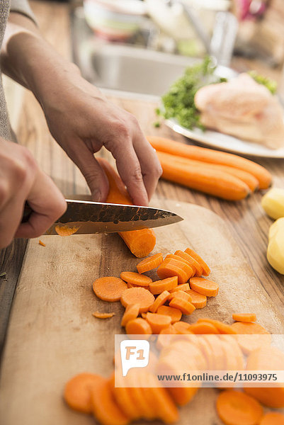 Frau schneidet Karotten auf einem Schneidebrett in der Küche
