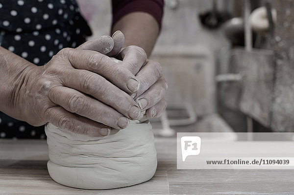 Close-up of female potter kneading clay on workbench  Bavaria  Germany