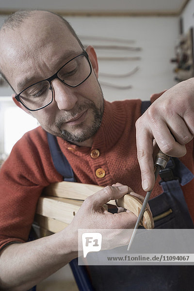 Männlicher Bogenbauer feilt die Spitzen eines Bogens in der Werkstatt  Bayern  Deutschland