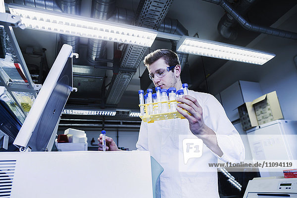 Junger männlicher Wissenschaftler untersucht ein Reagenzglas in einem Apothekenlabor