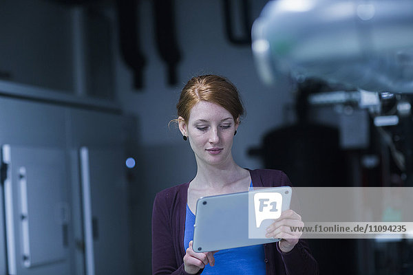 Junge Ingenieurin bei der Arbeit mit einem digitalen Tablet in einer Industrieanlage