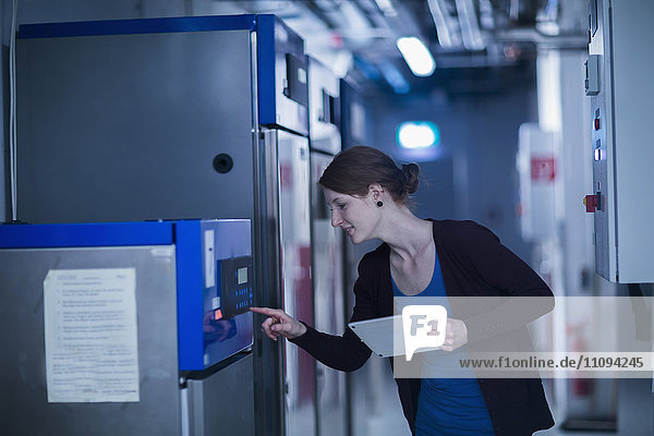 Young female engineer using a digital tablet and controlling a switchgear in control room