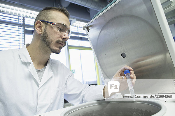 Junger männlicher Wissenschaftler untersucht ein Reagenzglas in einem Apothekenlabor
