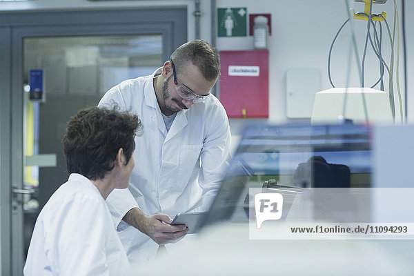 Two scientist working on digital tablet in a pharmacy laboratory