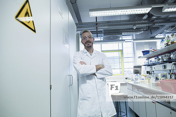 Scientist standing with arms crossed in a pharmacy laboratory
