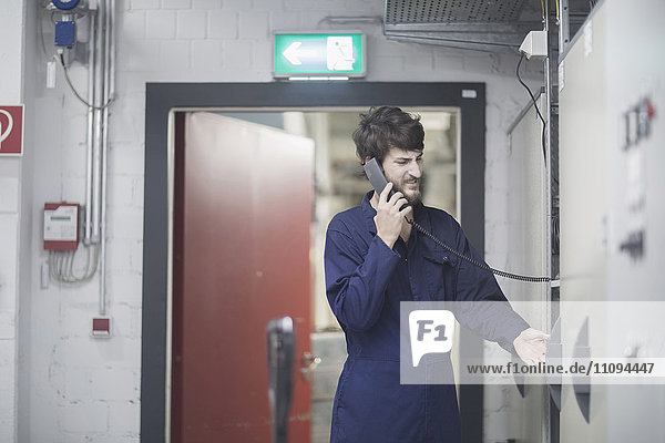 Young male engineer talking on landline phone in an industrial plant
