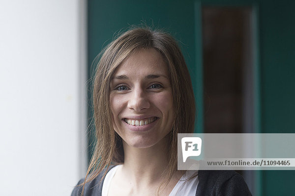 Porträt einer jungen Frau  die vor einer Haustür lächelt