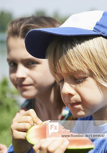 Kinder genießen ein Stück Wassermelone beim Picknick  München  Bayern  Deutschland