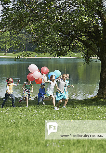 Kinder laufen im Park mit Luftballons  München  Bayern  Deutschland