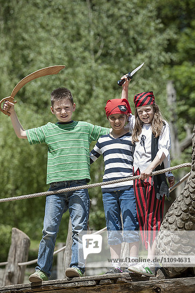 Drei als Piraten verkleidete Freunde spielen auf einem Piratenschiff auf einem Abenteuerspielplatz  Bayern  Deutschland