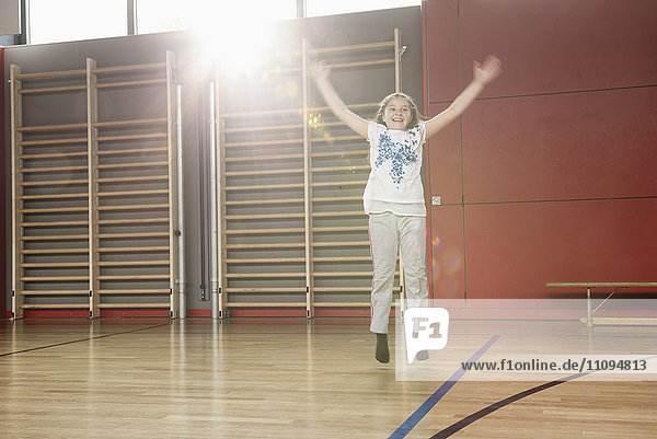 Fröhliches kleines Mädchen springt in Sporthalle  München  Bayern  Deutschland