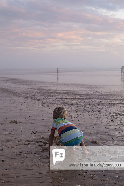 Rückansicht eines kleinen Kindes beim Muschelsuchen am Strand  Lit-et-Mixe  Frankreich