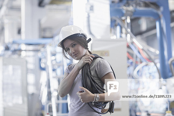 Porträt einer Technikerin  die eine Seilrolle auf der Schulter trägt  in einer Industrieanlage  Freiburg im Breisgau  Baden-Württemberg  Deutschland