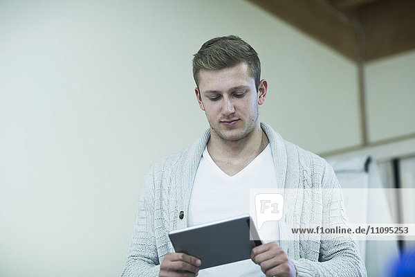 Young male teacher working on a digital tablet in classroom  Freiburg Im Breisgau  Baden-Württemberg  Germany